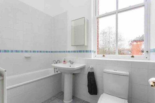 uma casa de banho branca com um lavatório, um WC e uma janela. em Luxury 2 BD, 2 BA on private gated Chigwell park em Chigwell
