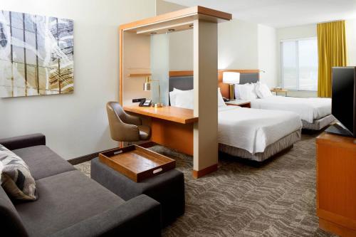 a hotel room with two beds and a desk and a couch at SpringHill Suites Houston NASA/Webster in Webster