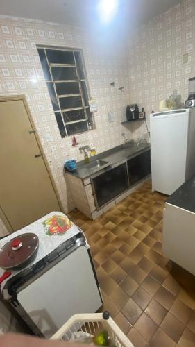 a small kitchen with a table and a refrigerator at Quarto Aconchegante in Cruzeiro