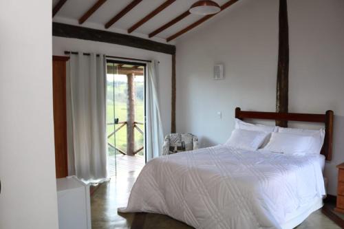 a bedroom with a white bed and a sliding glass door at Estalagem Sensações in Cunha