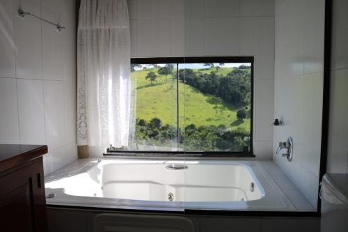 a bath tub in a bathroom with a window at Estalagem Sensações in Cunha