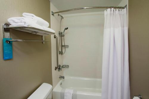 y baño con cortina de ducha blanca y aseo. en SpringHill Suites by Marriott Madera, en Madera