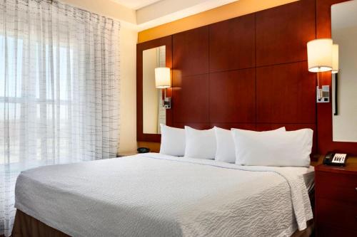 a hotel room with a large bed with white sheets at Residence Inn by Marriott Greensboro Airport in Greensboro