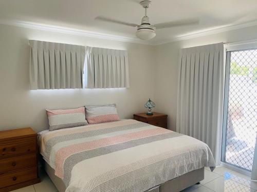 a white bedroom with a bed and a window at 62 Tingira Close - Modern lowset home with swimming pool, outdoor area, ample parking. Pet friendly in Rainbow Beach