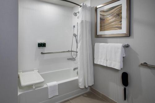 a bathroom with a shower and a bath tub with towels at Courtyard Fort Meade BWI Business District in Annapolis Junction