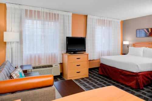 um quarto de hotel com uma cama e uma televisão de ecrã plano em TownePlace Suites Wichita East em Wichita