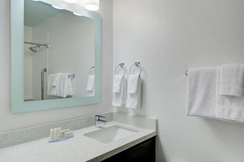 a bathroom with a sink and a mirror and towels at TownePlace Suites Wichita East in Wichita