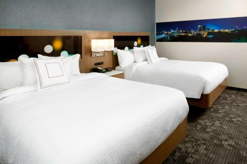 una camera d'albergo con due letti con lenzuola bianche di Courtyard by Marriott Akron Downtown ad Akron