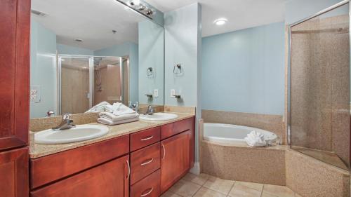 a bathroom with two sinks and a shower and a tub at Laketown Wharf #101 by Nautical Properties Vacation Rentals in Panama City Beach