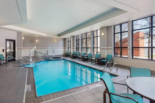 una piscina en una habitación de hotel con sillas y mesa en Residence Inn Louisville Downtown en Louisville