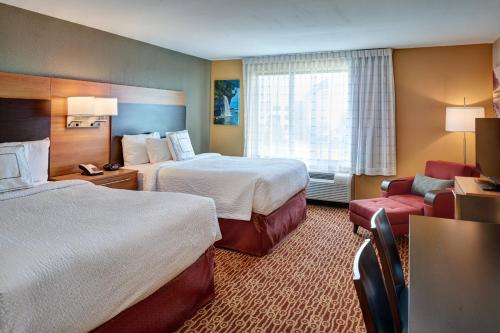 a hotel room with two beds and a chair at TownePlace Suites by Marriott Detroit Troy in Troy