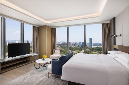 成都市にあるCourtyard by Marriott Chengdu Southの大型ベッドとテレビが備わるホテルルームです。