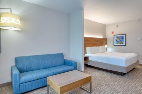 um quarto de hotel com uma cama e um sofá azul em Holiday Inn Express Troy, an IHG Hotel em Troy