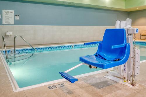 a swimming pool with a blue chair next to it at Holiday Inn Express Troy by IHG in Troy