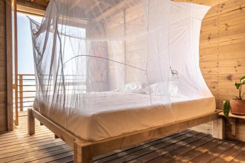 Cama en habitación de madera con mosquitera en Mendihuaca Surf Camp, en Guachaca