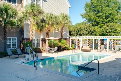 a swimming pool with palm trees and a house at Residence Inn Columbia Northeast/Fort Jackson Area in Columbia