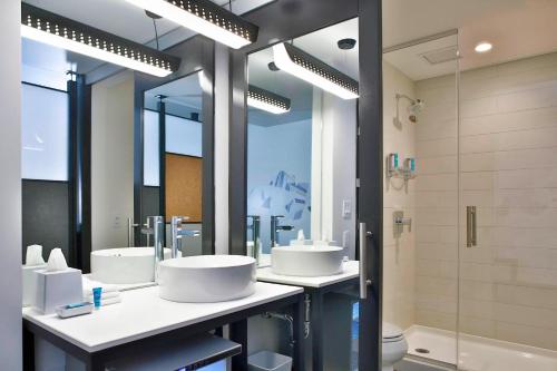 a bathroom with three sinks and a shower at Aloft Florence in Florence