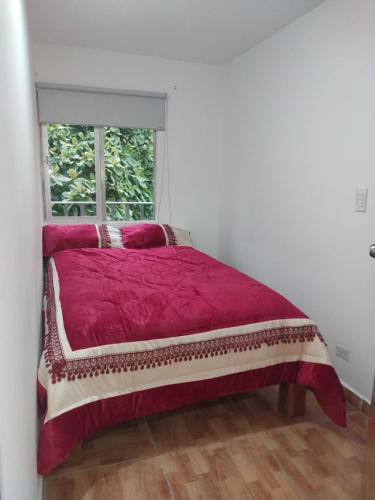 a bedroom with a red bed with a window at Los balcones l in Medellín