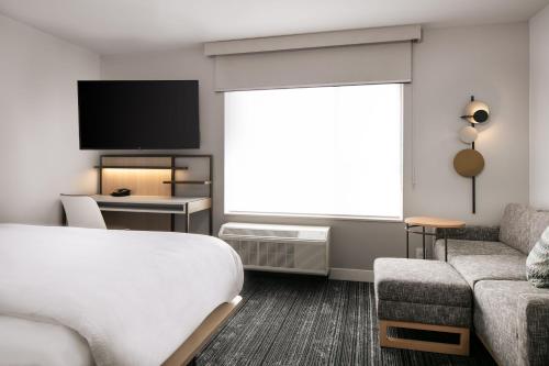 ein Hotelzimmer mit einem Bett, einem Sofa und einem TV in der Unterkunft TownePlace Suites by Marriott Oconomowoc in Oconomowoc