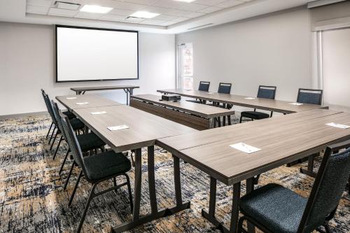 a conference room with tables and chairs and a screen at TownePlace Suites by Marriott Oconomowoc in Oconomowoc