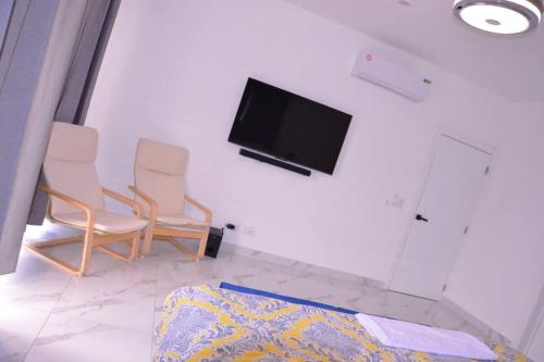 - un salon avec deux chaises et une télévision à écran plat dans l'établissement Villa Caleta Pool & Heated Jacuzzi, à La Romana