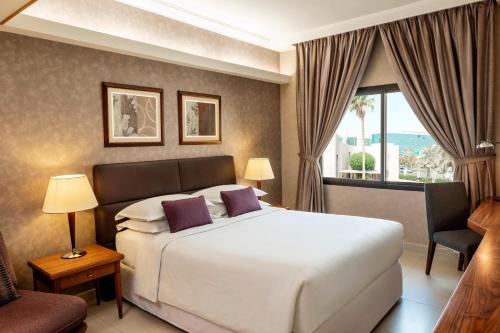 - une chambre avec un grand lit blanc et une fenêtre dans l'établissement Sheraton Riyadh Hotel & Towers, à Riyad