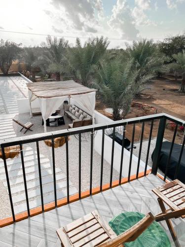 a balcony with a table and chairs and palm trees at The Farm Chalet in Al Ain