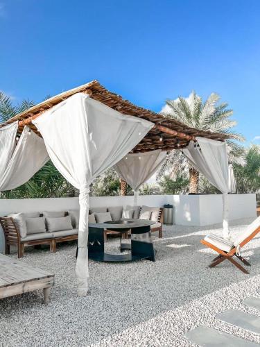 a patio with a white canopy and chairs and a table at The Farm Chalet in Al Ain
