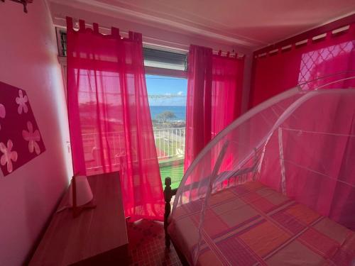 La résidence du sportif Bernard في Anse-Bertrand: غرفة نوم مع غرفة وردية مع نافذة
