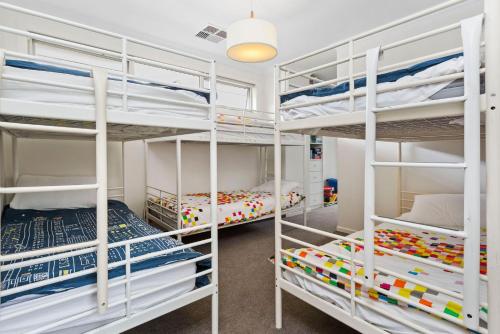 a bedroom with two bunk beds and a room with two beds at Corymbia Mount Martha in Mount Martha