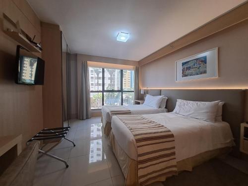 a hotel room with two beds and a television at Haus Flat particular em Brasilia in Brasilia