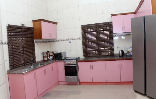 eine Küche mit rosa Schränken und einem Kühlschrank in der Unterkunft Laribond's Place in Lagos