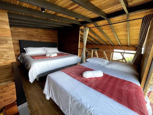una camera con 2 letti in una baita di tronchi di Entre Cumbres - Cabaña con vista a la cordillera 