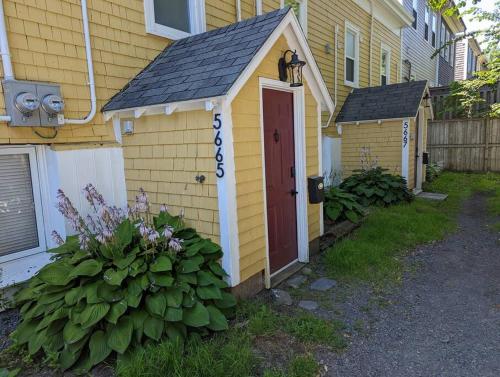 a small yellow house with a red door at Downtown one bedroom/Historic Bauer Terrace in Halifax