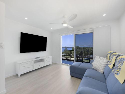 a living room with a blue couch and a flat screen tv at Clayton Garden Unit 5 Golden Beach in Golden Beach