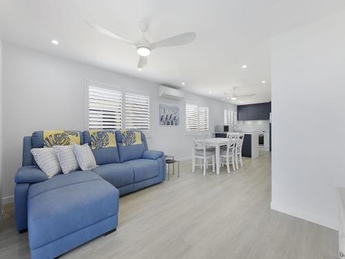 a living room with a blue couch and a kitchen at Clayton Garden Unit 5 Golden Beach in Golden Beach