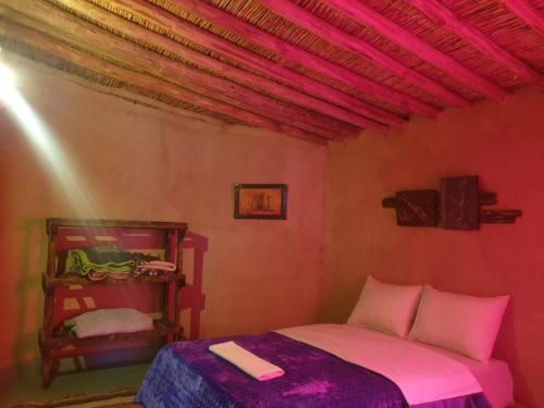 Cette petite chambre comprend un lit avec des draps roses. dans l'établissement ecolodge bivouac des aigles, à Ouarzazate
