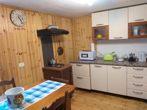 a kitchen with a table and a clock on the wall at Casa Mimosa 1 in Gressan