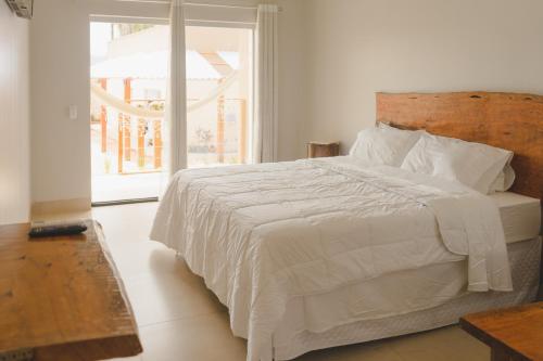 a bedroom with a white bed with a large window at Pousada Paraiso in Alto Paraíso de Goiás