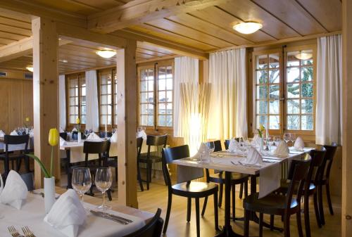 restauracja z białymi stołami, krzesłami i oknami w obiekcie Restaurant Hotel Rüttihubelbad w mieście Walkringen