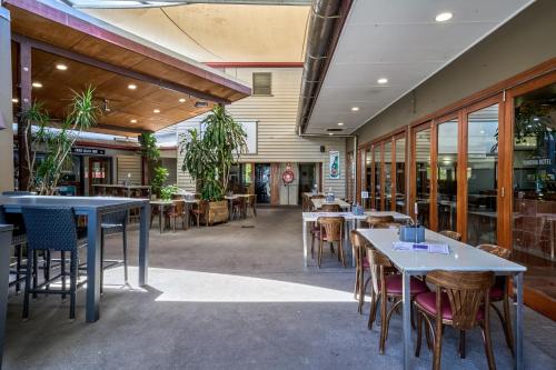a restaurant with tables and chairs and windows at Yandina Hotel in Yandina