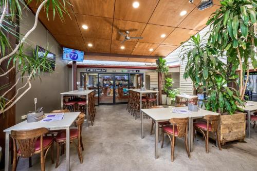 a restaurant with tables and chairs and plants at Yandina Hotel in Yandina