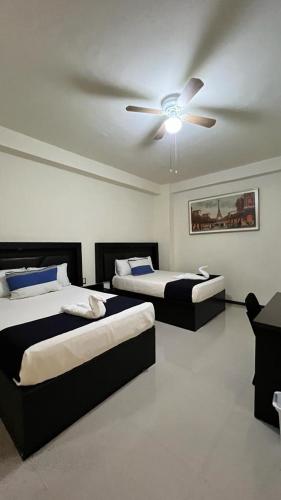 two beds in a room with a ceiling fan at Hotel Real Jaguar in Tuxtla Gutiérrez
