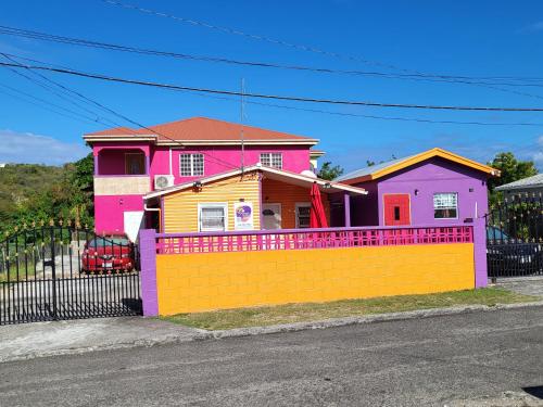 a pink and yellow house with a fence at Tequila Sunrise Antigua in Osbourn