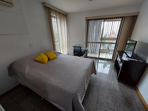 a bedroom with a bed with yellow pillows and a television at Loft Espaçoso e Aconchegante in Niterói