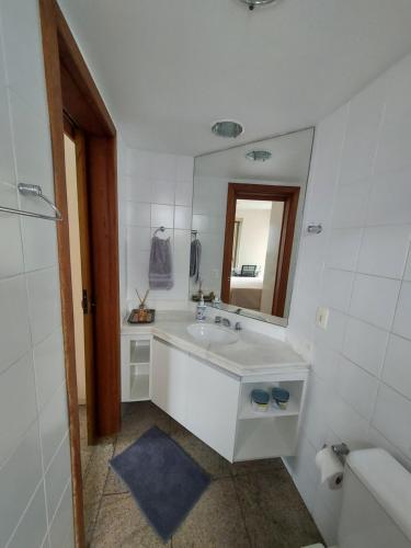 a white bathroom with a sink and a mirror at Loft Espaçoso e Aconchegante in Niterói