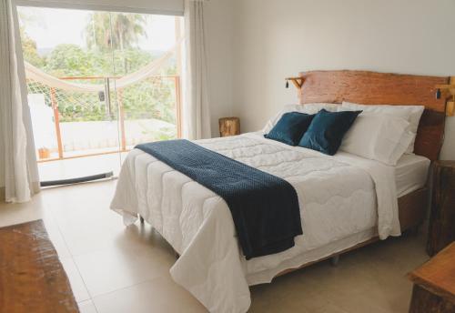 a bedroom with a bed with blue pillows and a window at Pousada Paraiso in Alto Paraíso de Goiás