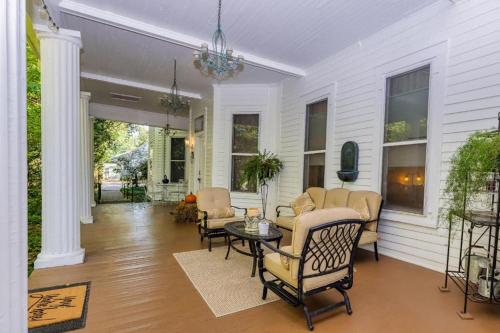 un porche de una casa blanca con sillas y mesa en Veranda Historic Inn 