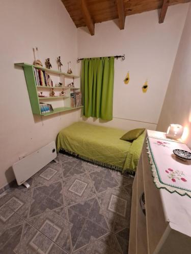 Un dormitorio con una cama verde y una mesa en Alem Casa de Familia en Ushuaia