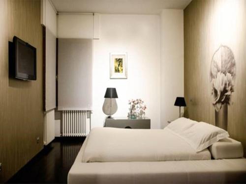 um quarto com uma grande cama branca e uma televisão em Villa Magnolie em Corbetta